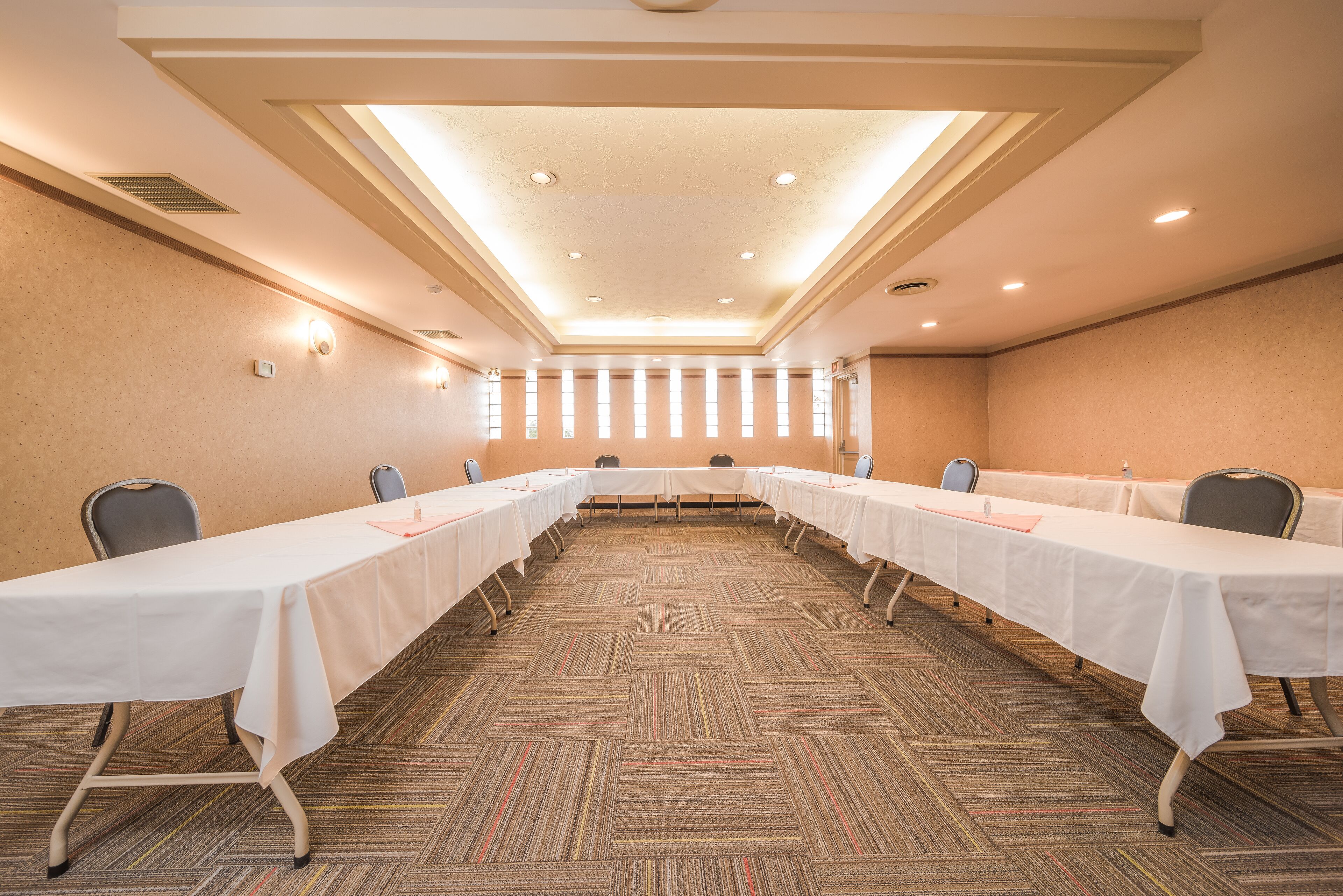 A conference room with a long table, chairs, and a carpeted floor.