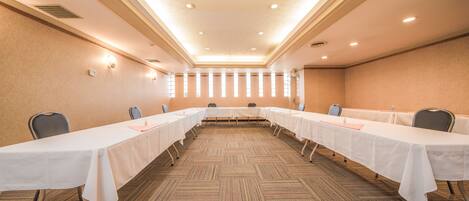 A conference room with a long table, chairs, and a carpeted floor.