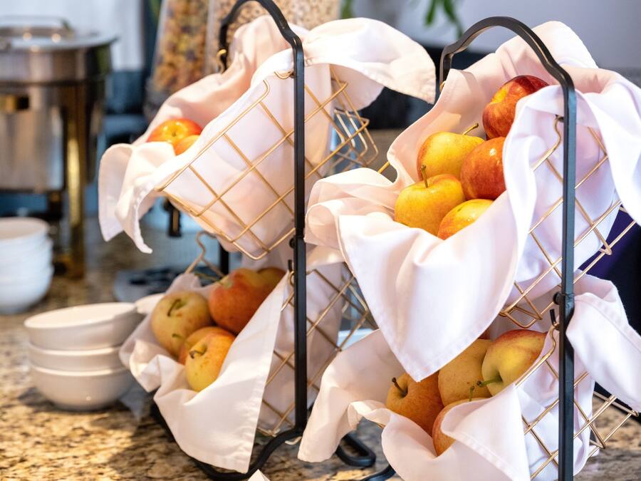 A buffet setup with fruit baskets and dessert cups on a granite countertop.
