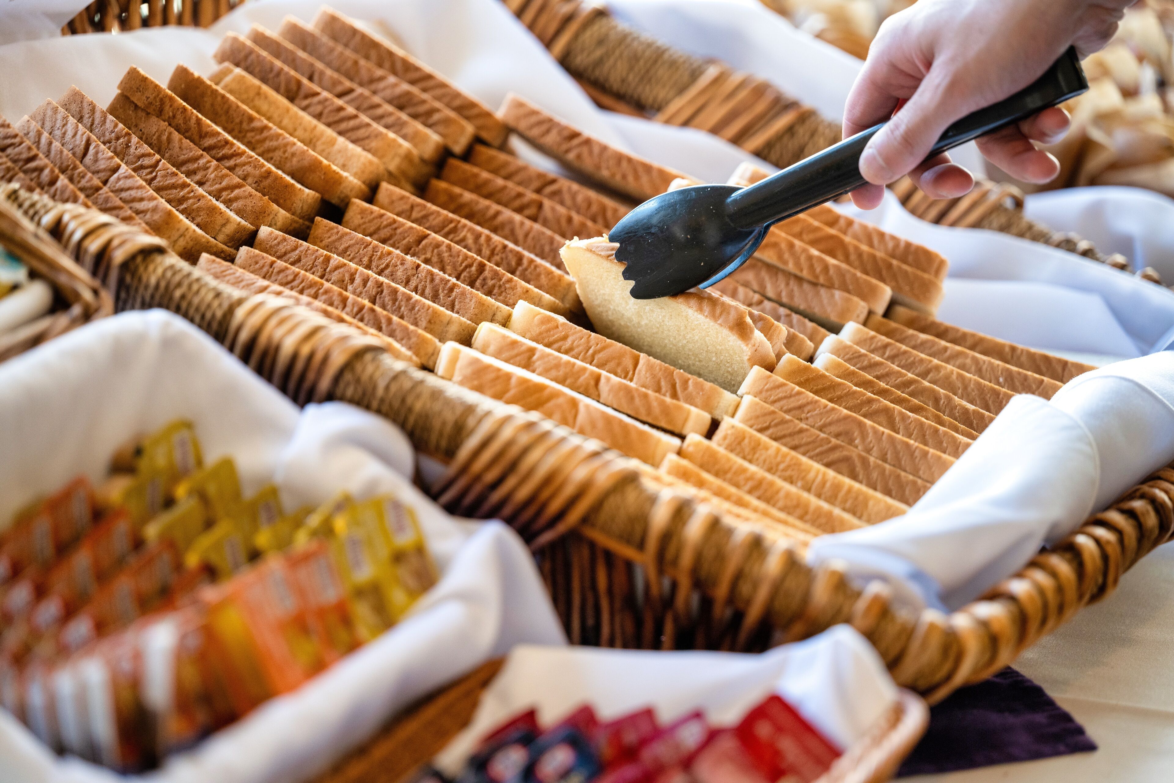 A buffet with neatly arranged bread and condiments.