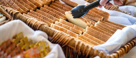 A buffet with neatly arranged bread and condiments.