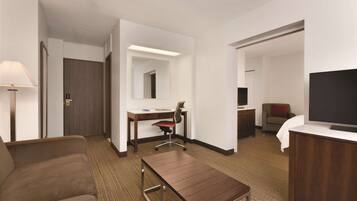 Una habitación de hotel con una cama, un escritorio, una silla, un televisor y una lámpara.