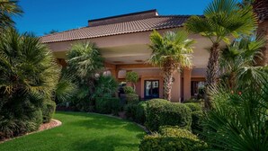 A modern building with a tiled roof, surrounded by well-maintained greenery and palm trees. - Quality Inn Saint George South Bluff (St. George)