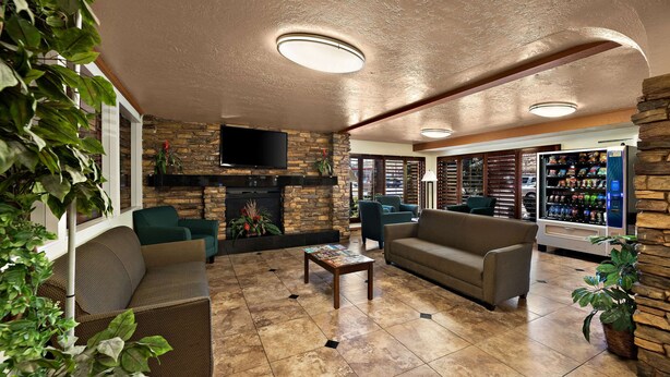 A spacious lounge area with a stone fireplace, comfortable seating, and a vending machine. - Quality Inn Saint George South Bluff (St. George)