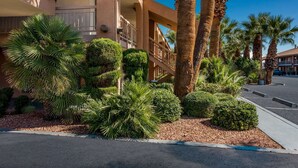 A hotel with a modern architectural design, featuring a balcony with a railing, palm trees, and well-maintained landscaping. - Quality Inn Saint George South Bluff (St. George)