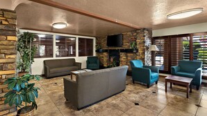 A living room with a stone fireplace, a sofa, two armchairs, and a coffee table. - Quality Inn Saint George South Bluff (St. George)