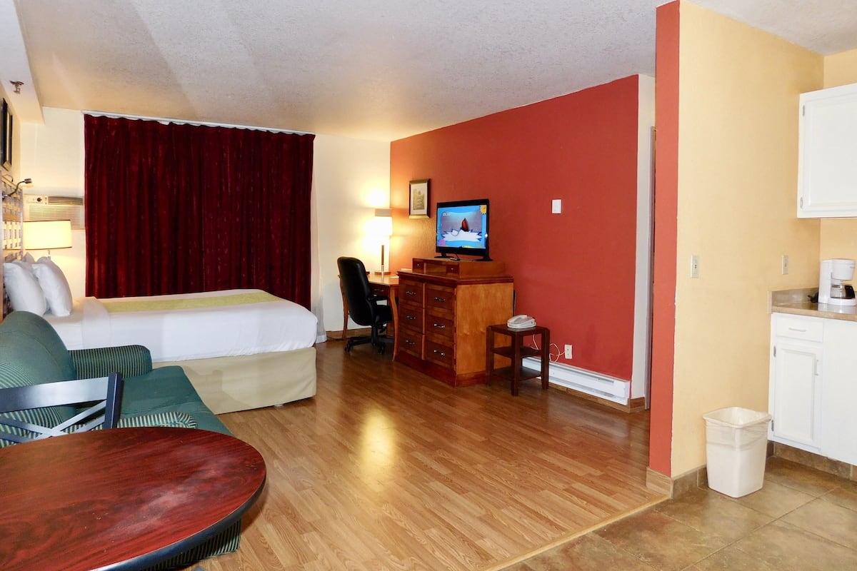 Une chambre d’hôtel comprenant un lit, un bureau avec une télévision, une chaise et une petite table.