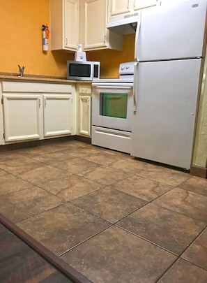 Una cocina con armarios blancos, microondas, horno y refrigerador.