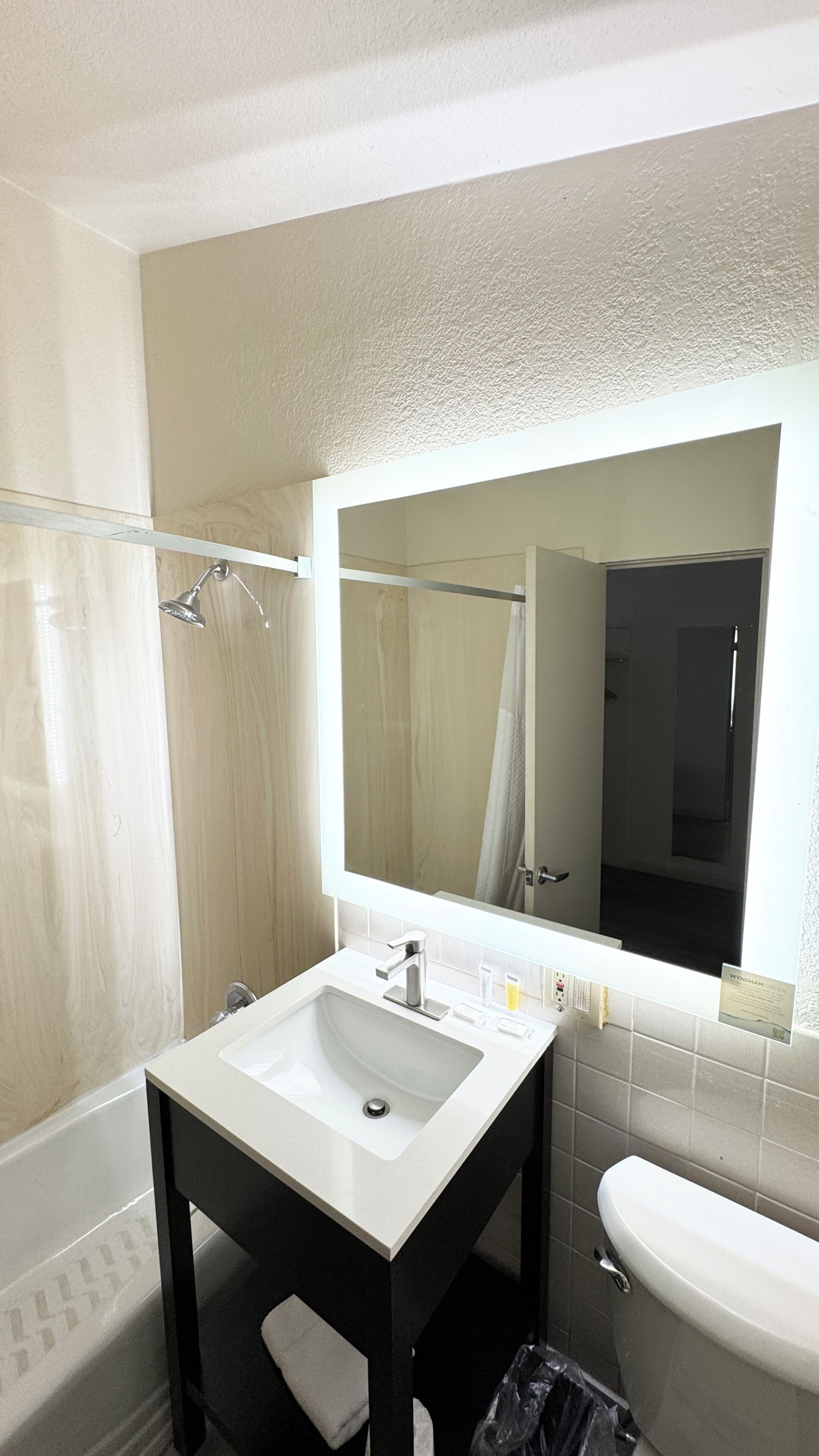 A bathroom with a white sink, a mirror, a shower, and a toilet.