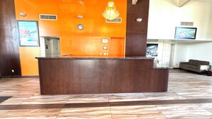 Una recepció amb un rellotge, una làmpada de cristall i un quadre al mur.