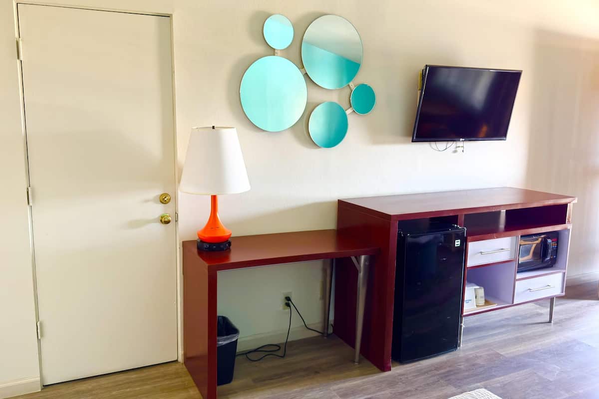 Une pièce comprenant un bureau, une télévision, une lampe, un réfrigérateur et une poubelle.