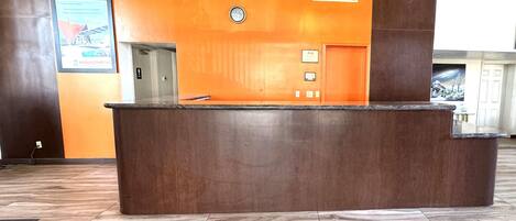 A reception desk with a marble floor, a clock, and a chandelier.