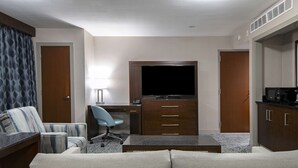 A hotel room with a sofa, a desk with a chair, a television, and a kitchenette. - Doubletree by Hilton Hotel Kamloops (Kamloops)