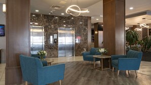 A lobby with a marble wall, an elevator, and blue seating. - Doubletree by Hilton Hotel Kamloops (Kamloops)