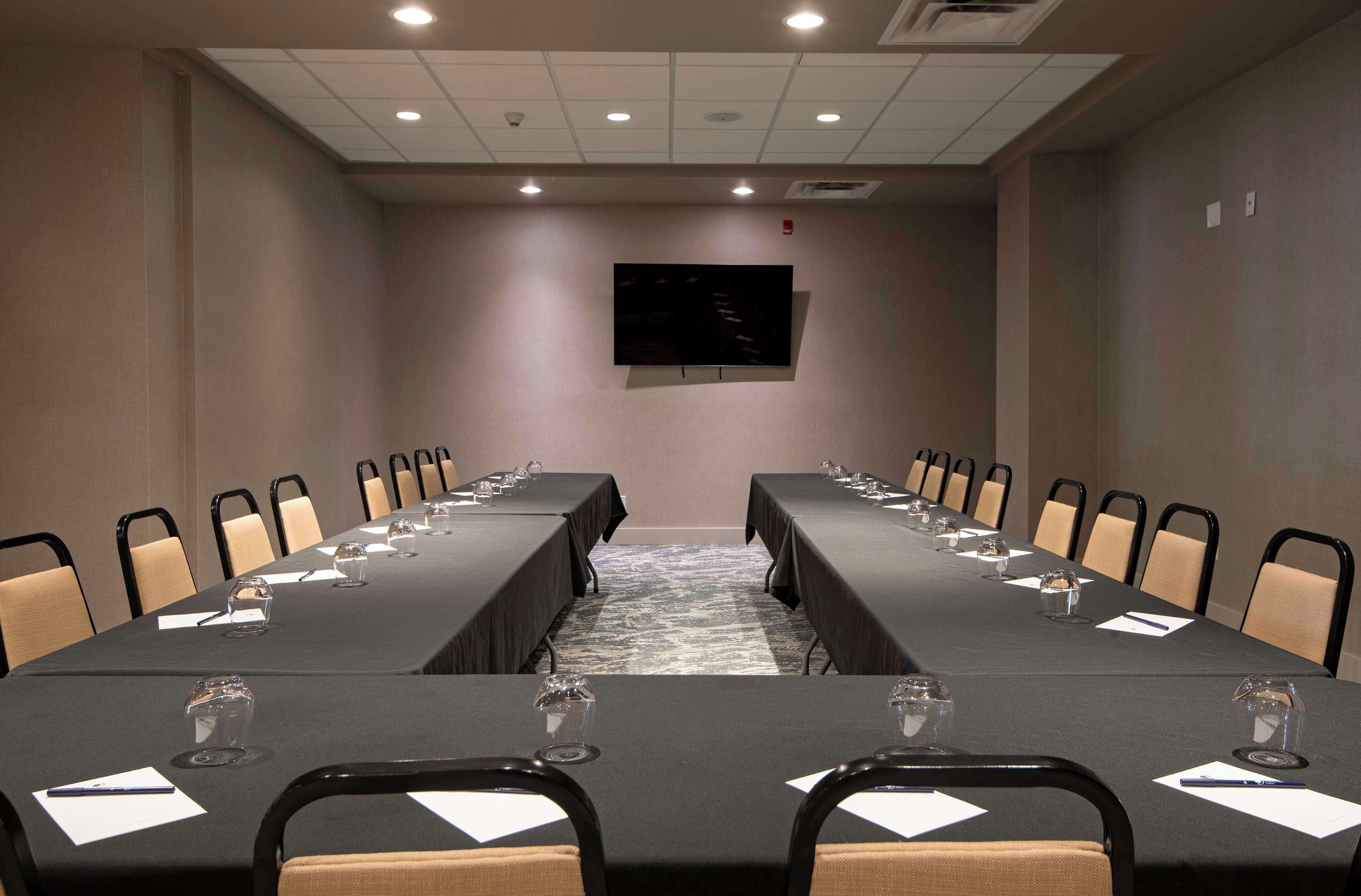 A conference room with a long table, chairs, and a flat-screen TV on the wall.