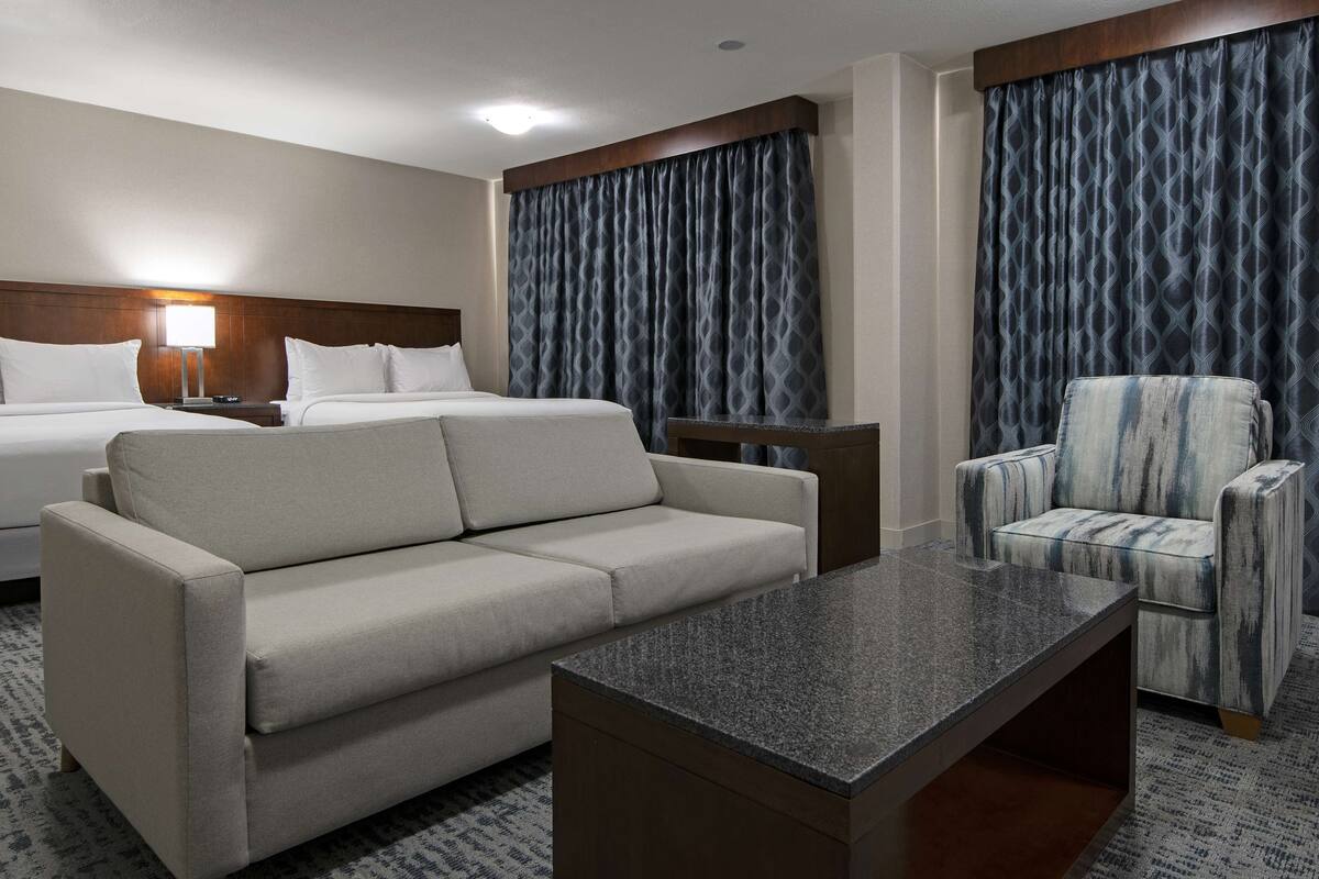 A hotel room with a bed, a sofa, a chair, and a small table.