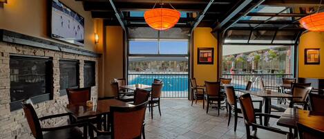 A restaurant with outdoor seating, a pool view, and a fireplace.