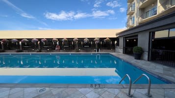 Piscina con indicador de profundidad de 2,4 metros, rodeada de sillas de descanso y plantas en macetas.