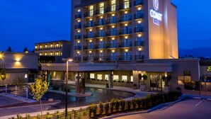 Un hotel de varios pisos con un patio central, piscina y zona de estacionamiento.