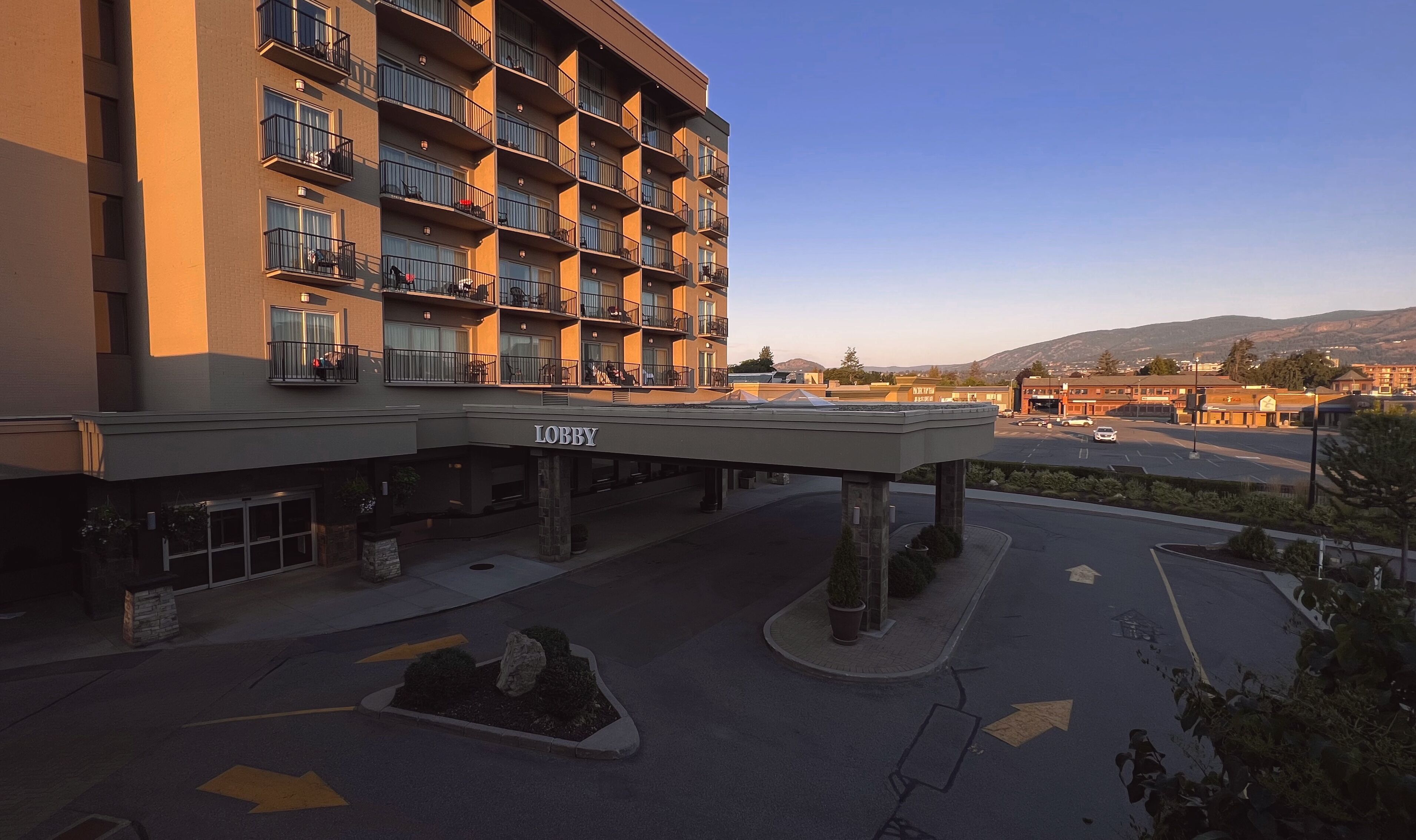 A multi-story hotel with balconies, a lobby area, and a parking lot.