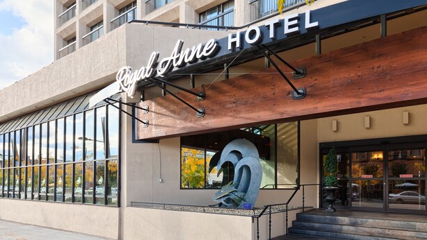 Exterior del Hotel Royal Anne con una gran escultura de metal en primer plano, fachada moderna y una vista despejada de la calle.
