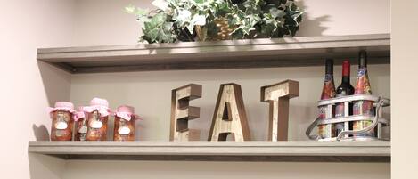 Una repisa con frascos, letras de madera que deletrean "EAT", y botellas.