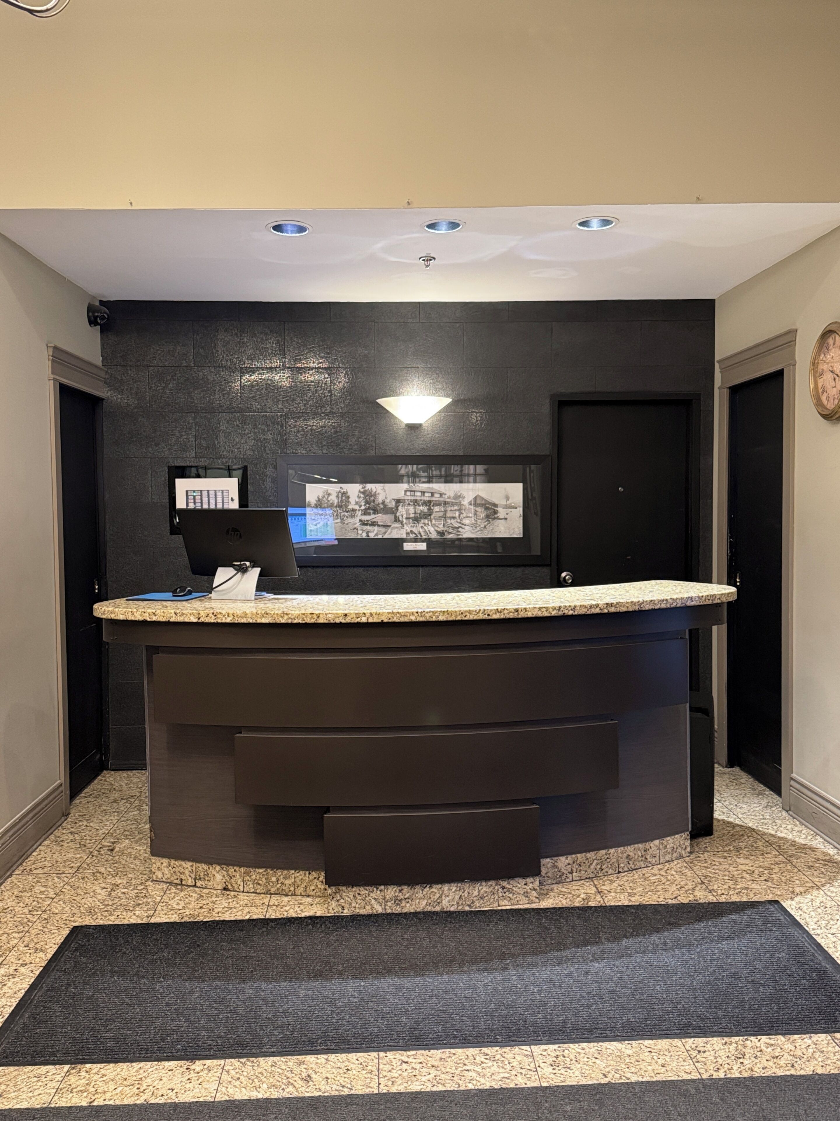 A reception desk with a computer, a framed photo, and a clock on the wall.