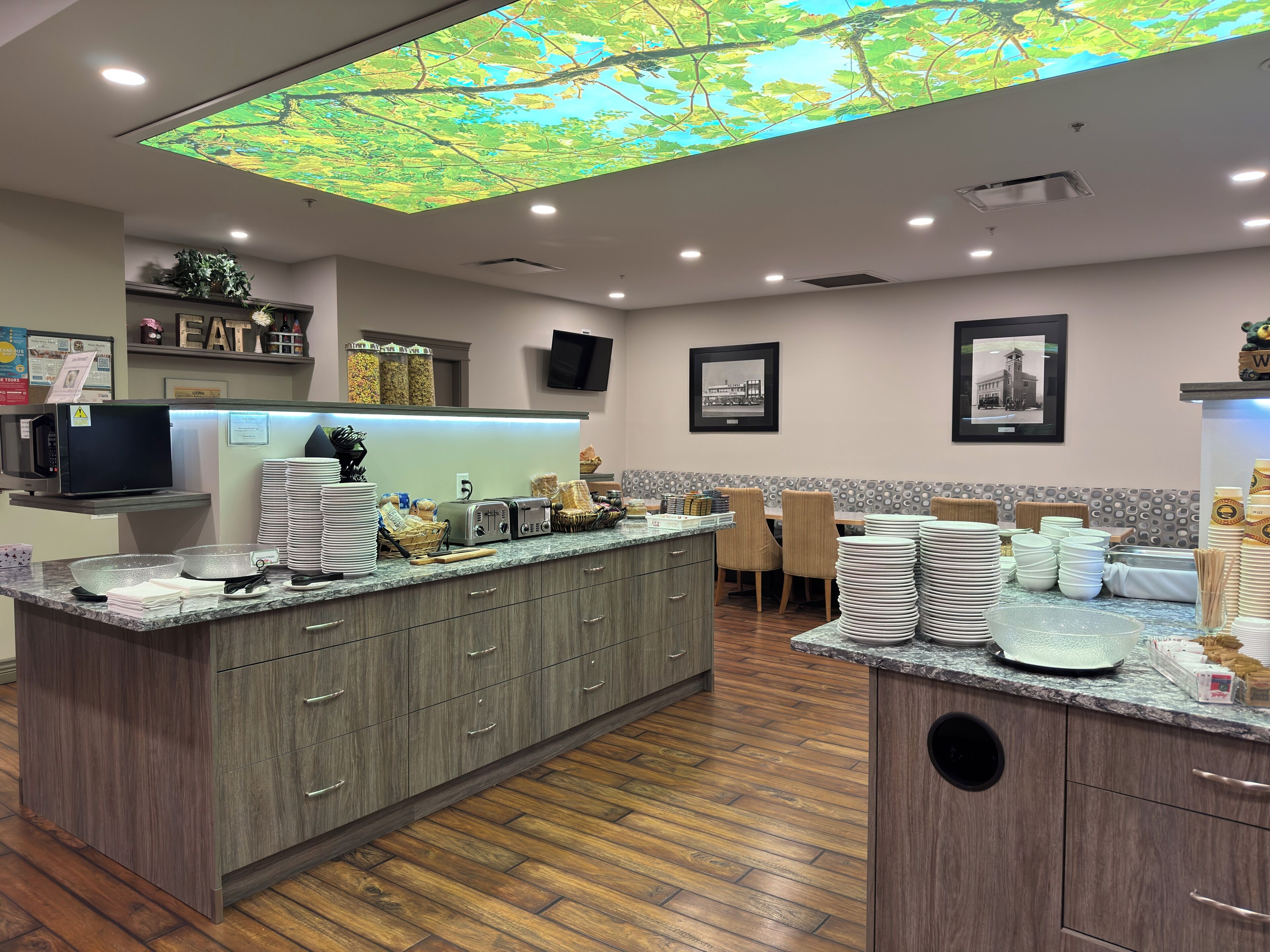 A modern kitchen with a central island, wooden cabinets, and a ceiling with a nature-themed light display.