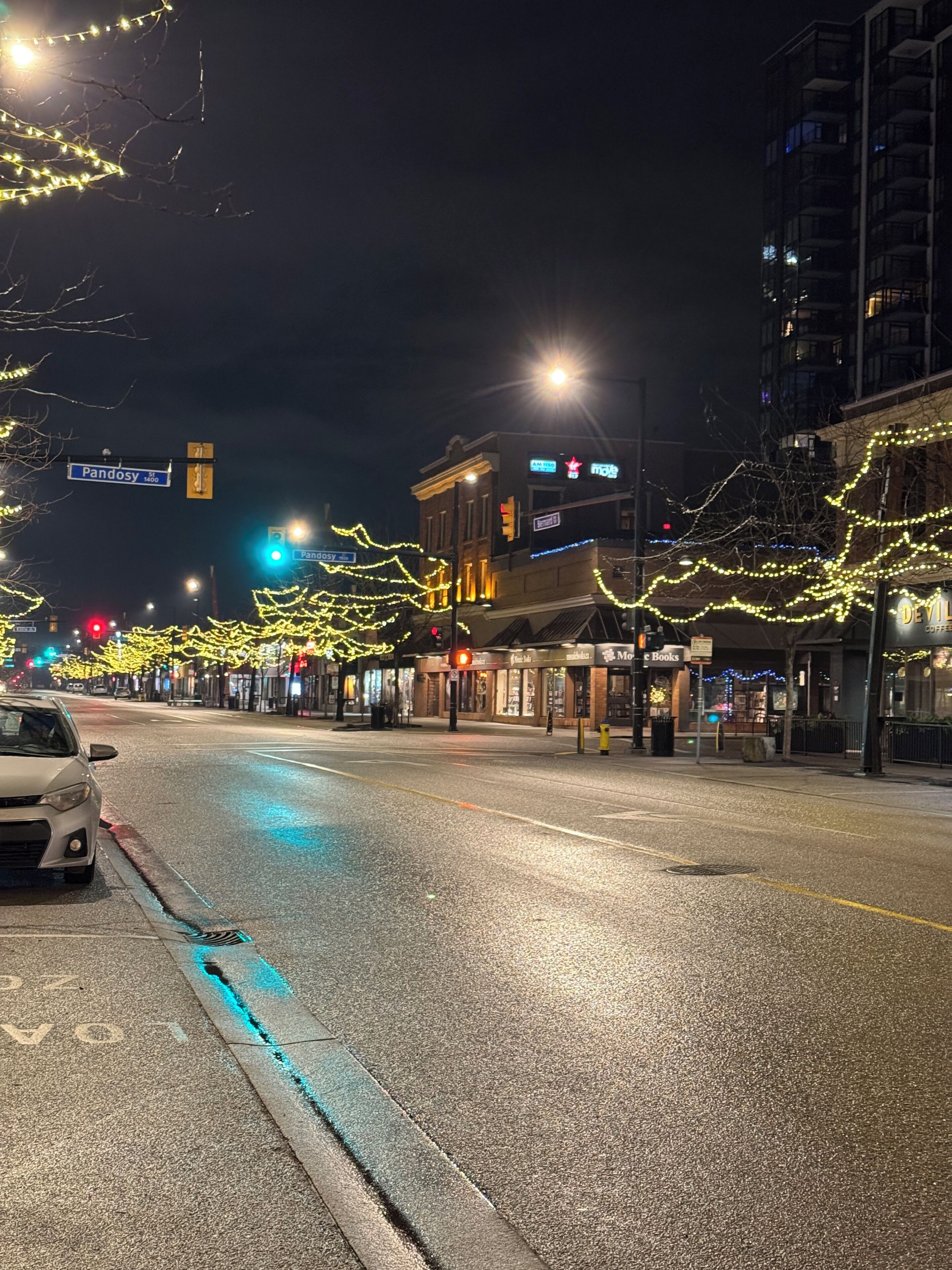 A street with buildings, a car, and streetlights.