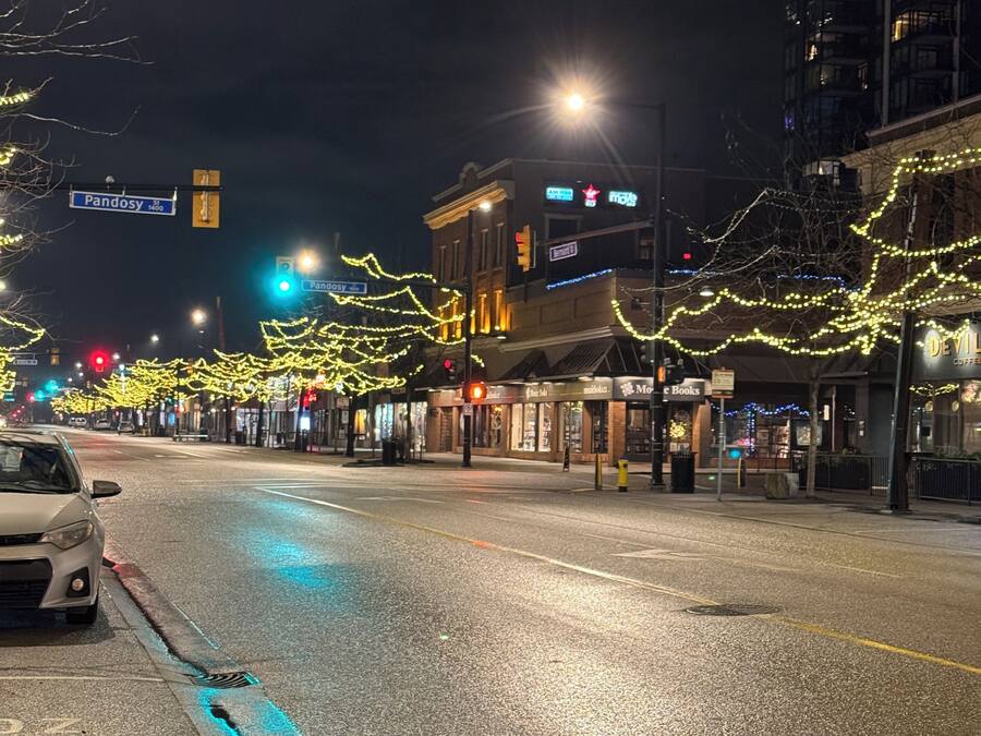 A street with buildings, a car, and streetlights.