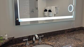 Une salle de bain avec un grand miroir, un lavabo et une douche.