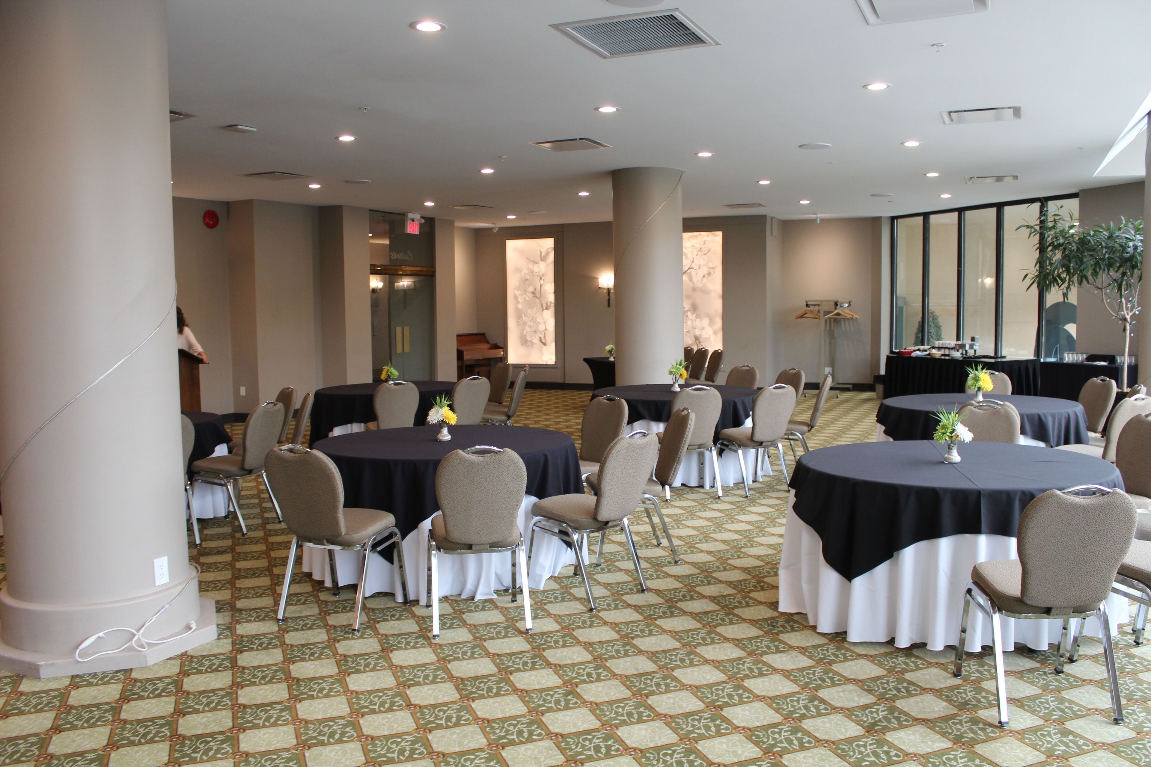 Un salón de conferencias con mesas redondas, sillas y un piano.