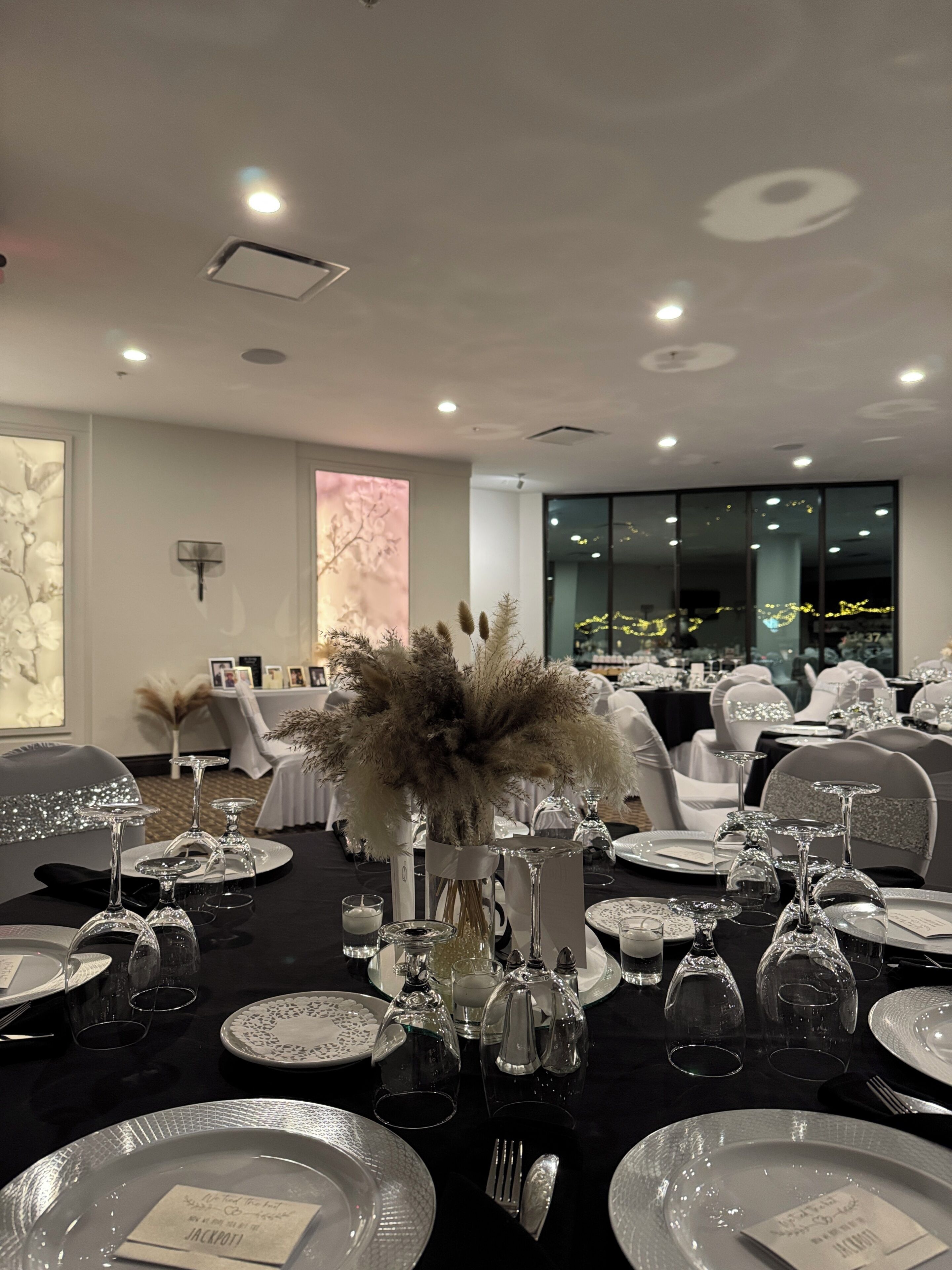 A formal dining room with tables set for a meal, featuring glassware and floral centerpieces.