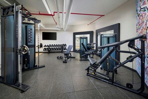 Un gimnasio con diversos equipos de ejercicio, incluyendo máquinas de pesas y mancuernas.