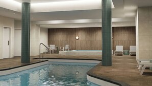 An indoor swimming pool with a wooden wall and seating area. - Ômage Hotel, Montreal Laval, a Tribute Portfolio Hotel (Laval)