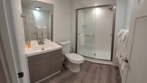 Ein modernes Badezimmer mit Duschkabine aus Glas, einem weißen Waschbecken mit Spiegel und einer Toilette.