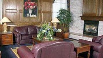 Una habitación con chimenea, sillones de cuero, una mesa de centro de madera y un cuadro de flores.