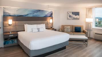 Une chambre d’hôtel moderne avec un grand lit, un canapé, un tableau et une vue sur la ville.