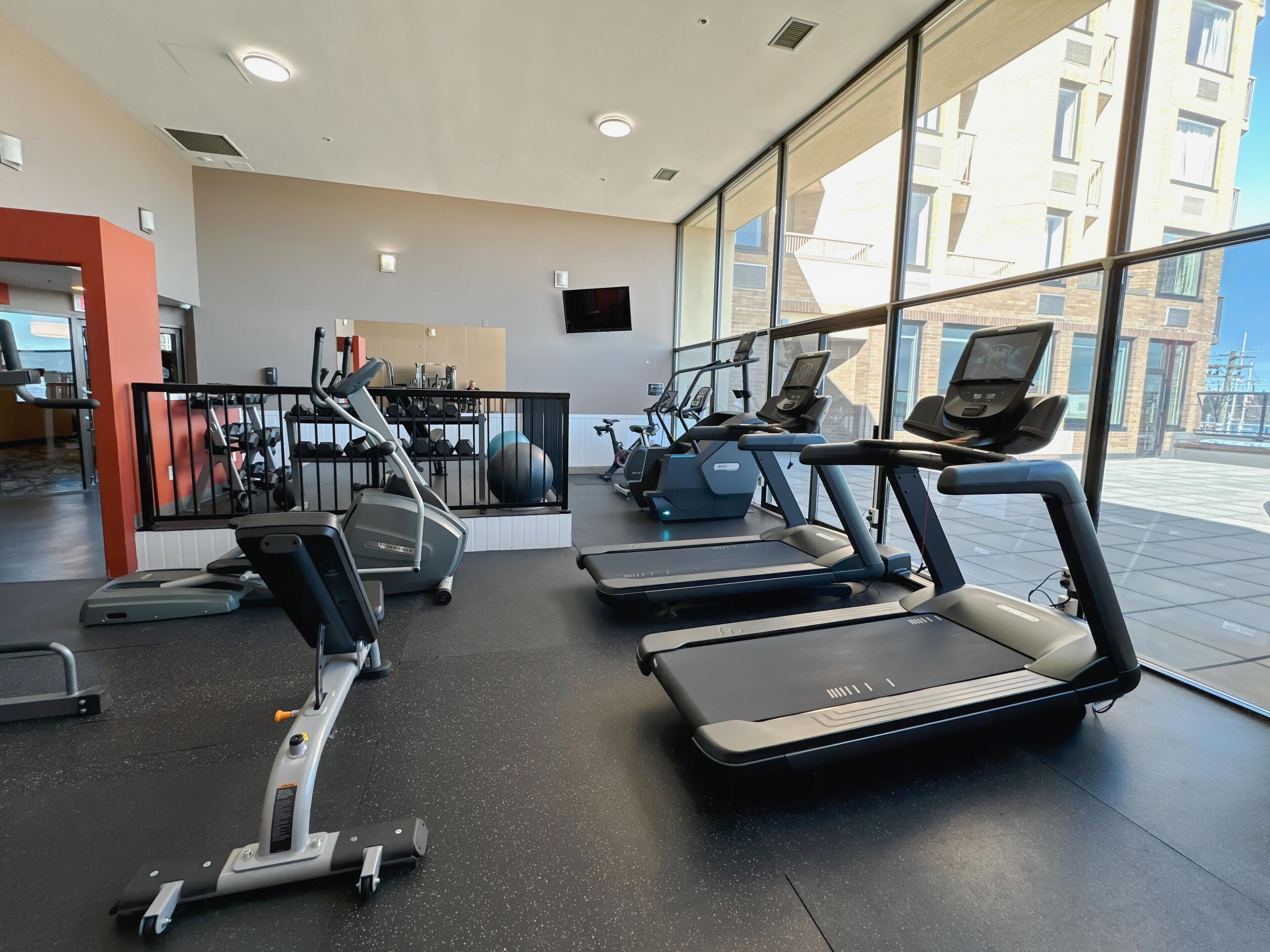 A modern gym with treadmills, elliptical machines, and weights.