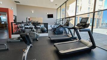 A modern gym with treadmills, elliptical machines, and weights.