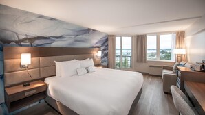 Una habitación de hotel moderna con una cama grande, un escritorio y vistas a la ciudad.