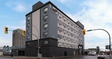 Un hotel moderno con un llamativo letrero 'Prestige', varios pisos y ubicación en una esquina, en la intersección de dos calles.