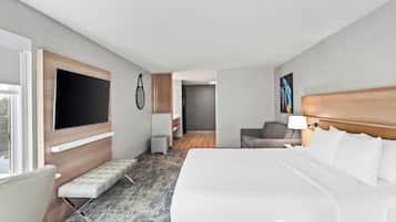 Una habitación de hotel con una cama grande, una zona de estar, un televisor y un cuadro en la pared.