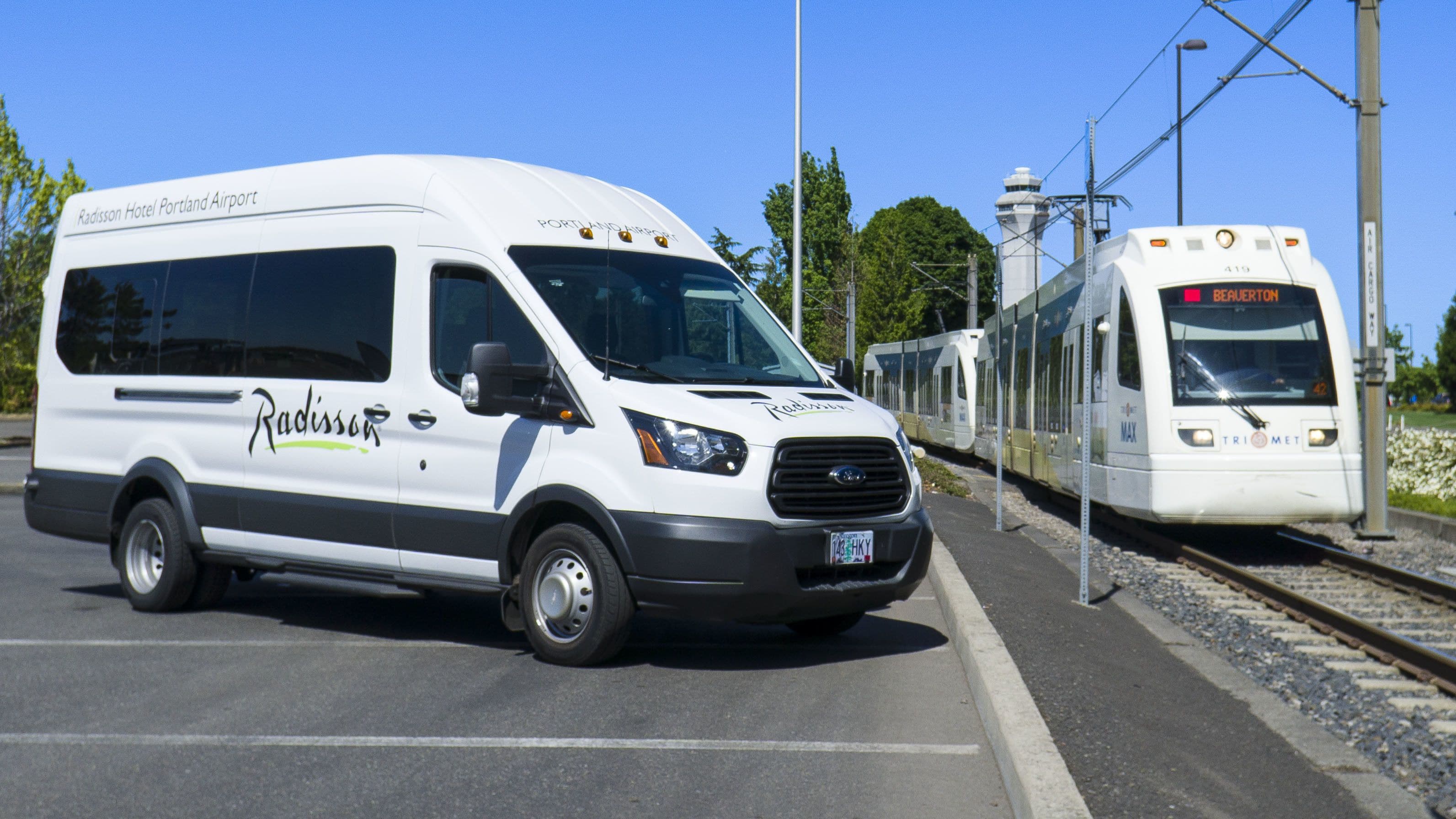 Una camioneta Radisson Hotel Portland Airport estacionada al lado de una vía de tren.