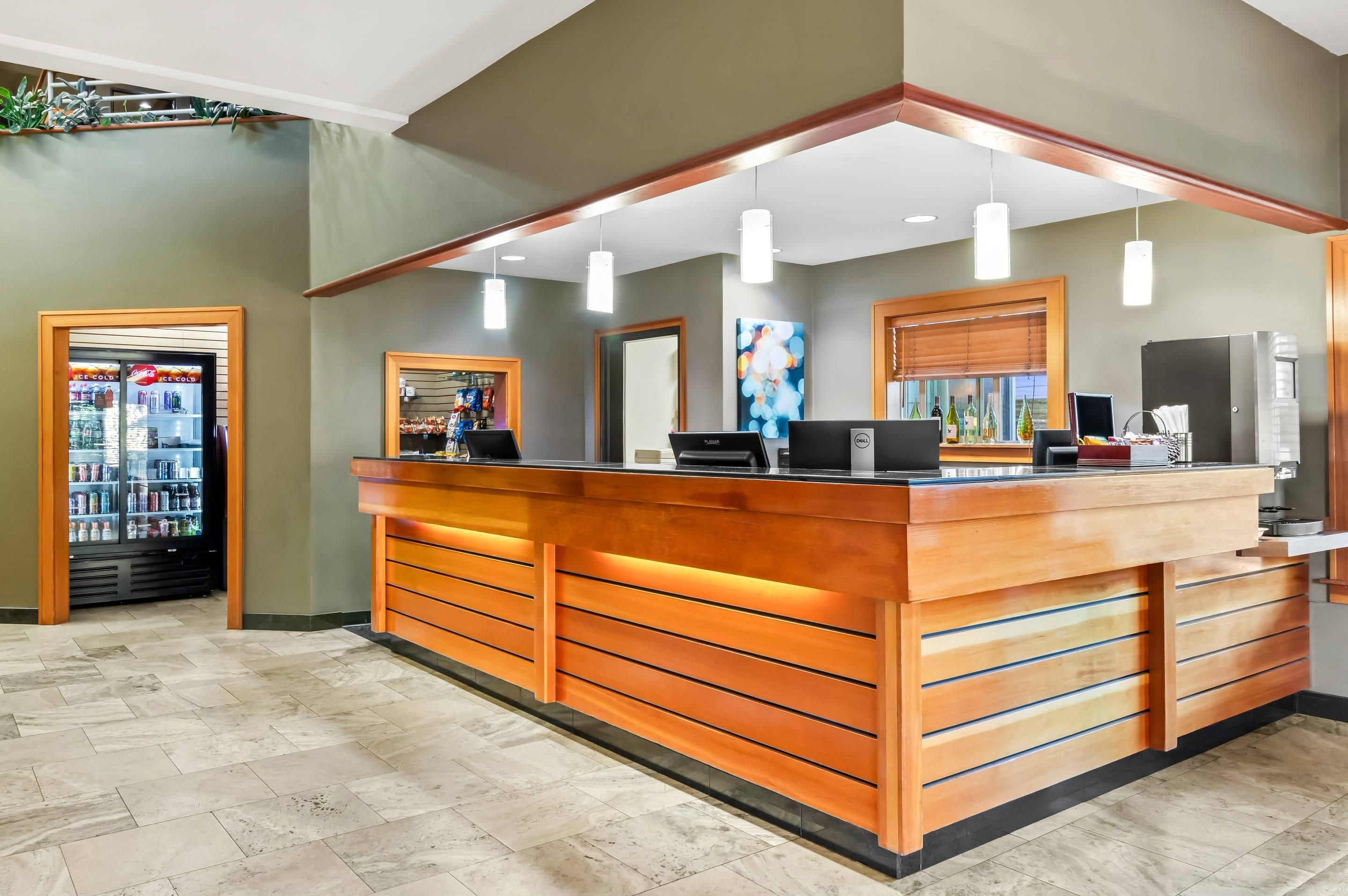 A reception desk with a wooden finish, a refrigerator, and a vending machine.