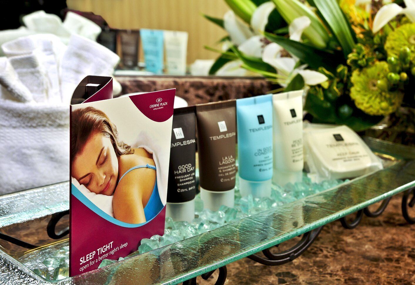 A display of Templespa products on a glass table with a floral arrangement in the background.