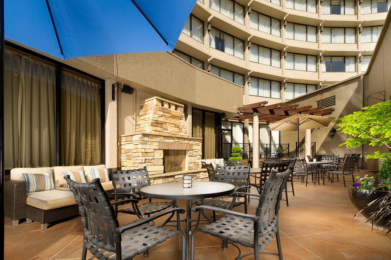 Un patio al aire libre con chimenea de piedra, asientos exteriores y vistas a los balcones del interior del edificio.