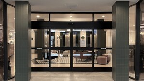 A hotel lobby with a glass door entrance, a reception desk, and seating area. - Crowne Plaza Portland Downtown Convention Center by IHG (Portland)