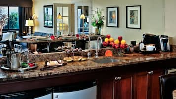 A well-equipped kitchen with a marble countertop, a coffee machine, and a variety of food items.
