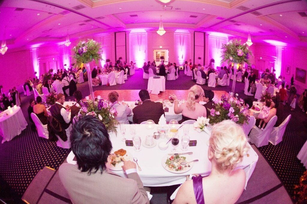 A banquet hall with round tables, white tablecloths, and floral centerpieces.